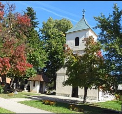 Црква у Сирогојну - Поглед на звоник и кровну конструкцију храма приказане из доњег угла за наглашавање масивности  Црква у Сирогојну снимљена споља са фокусом на камене елементе и православни крст на врху  Прочеље храма Светих апостола Петра и Павла које вековима дочекује вернике и намернике